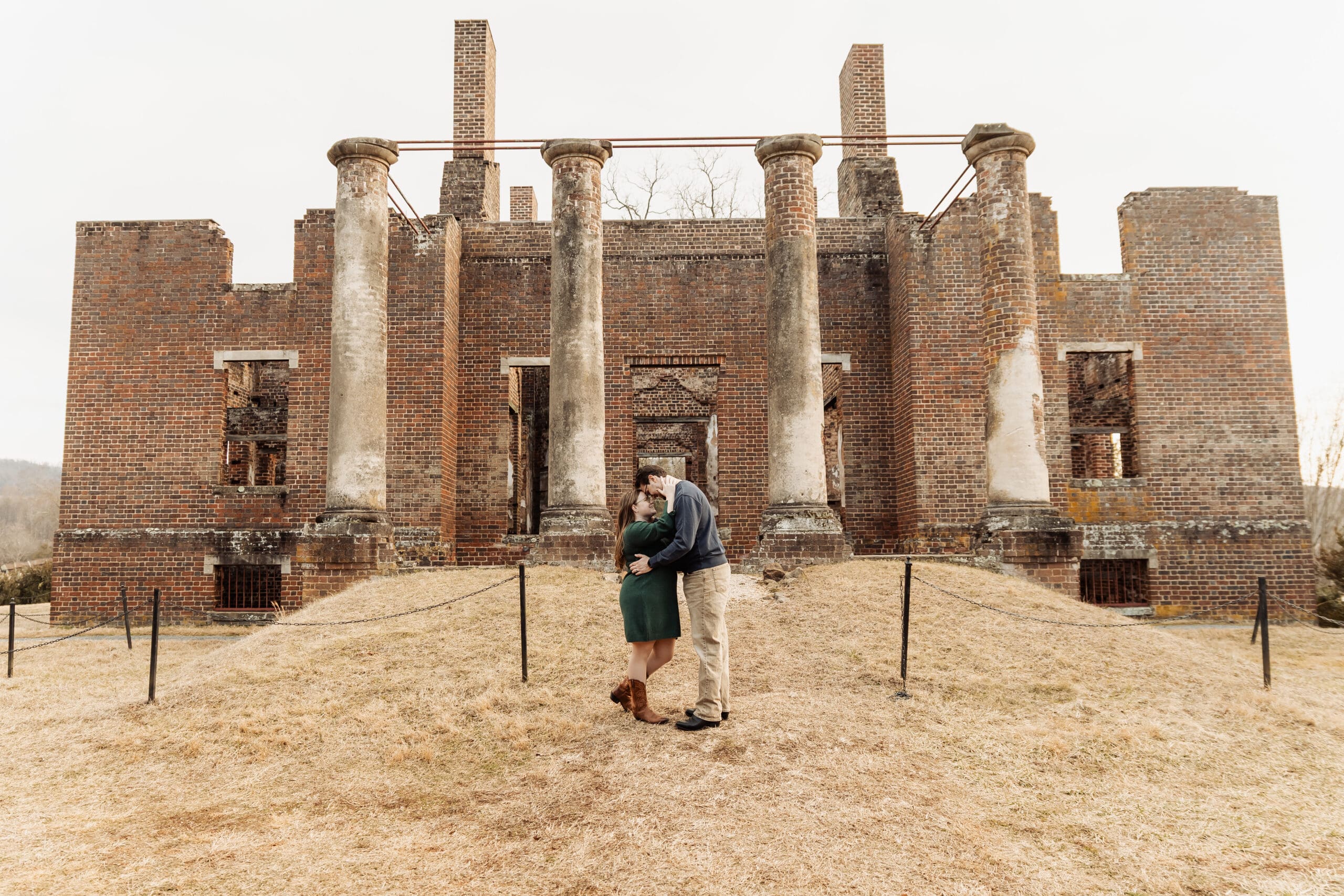 Engaged couple embracing in front of the historic brick columns at the Barboursville Ruins in Barboursville, Virginia